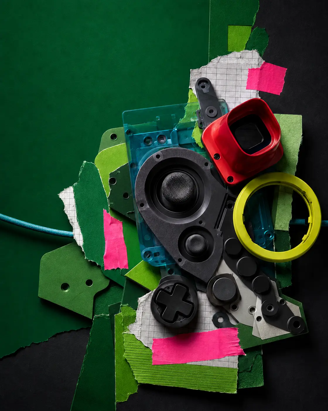 Layered control-deck collage of abstract game hardware, acrylic reflections and torn grid paper on green